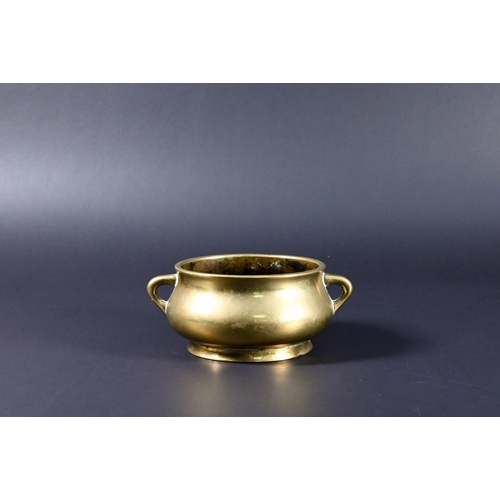 381 - A 19th century Chinese bronze small censer of compressed globular form with looped side handles stan... 