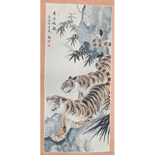 391 - A 20th century Chinese scroll painting of two prowling tigers in a mountainous landscape, inscriptio... 