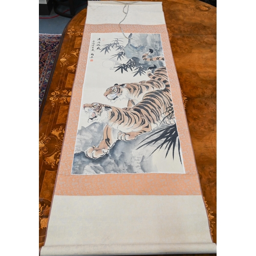 391 - A 20th century Chinese scroll painting of two prowling tigers in a mountainous landscape, inscriptio... 