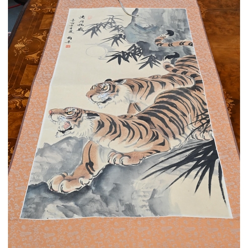 391 - A 20th century Chinese scroll painting of two prowling tigers in a mountainous landscape, inscriptio... 