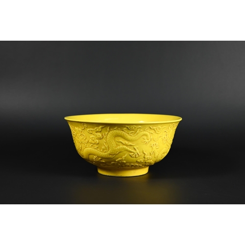 393 - A Chinese yellow glazed bowl, the exterior decorated in relief with dragons amongst stylised clouds,... 