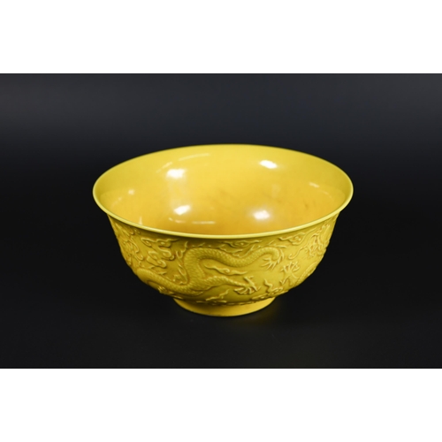 393 - A Chinese yellow glazed bowl, the exterior decorated in relief with dragons amongst stylised clouds,... 