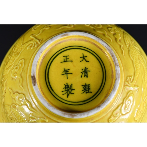 393 - A Chinese yellow glazed bowl, the exterior decorated in relief with dragons amongst stylised clouds,... 