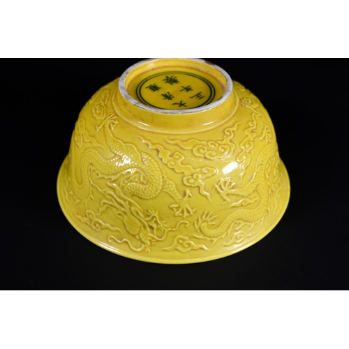 393 - A Chinese yellow glazed bowl, the exterior decorated in relief with dragons amongst stylised clouds,... 