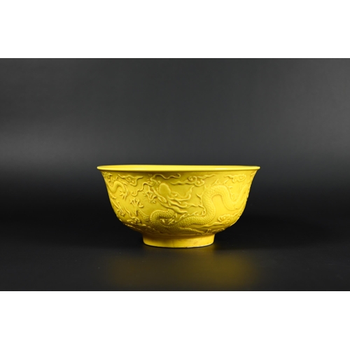 393 - A Chinese yellow glazed bowl, the exterior decorated in relief with dragons amongst stylised clouds,... 