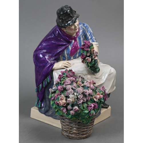 468 - A Charles Vyse Chelsea pottery figure of a flower-seller, seated with her basket of blooms, blue pai... 