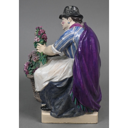 468 - A Charles Vyse Chelsea pottery figure of a flower-seller, seated with her basket of blooms, blue pai... 