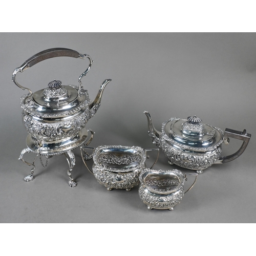 63 - An Edwardian silver four-piece tea service including kettle on stand, with embossed and chased decor... 