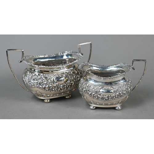 63 - An Edwardian silver four-piece tea service including kettle on stand, with embossed and chased decor... 