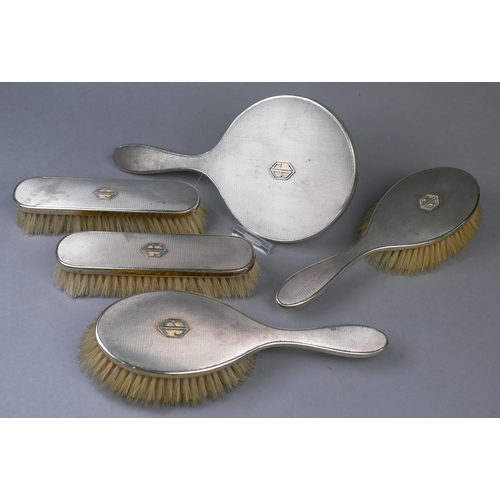 73 - An Asprey Art Deco silver gilt five-piece brush set including hand mirror, with engine-turned decora... 