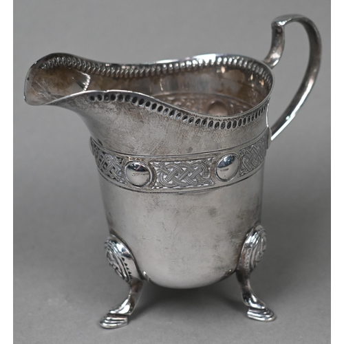 86 - An Irish silver cream jug with Celtic strapwork frieze and hoof feet, Dublin 1914, to/w four pairs o... 