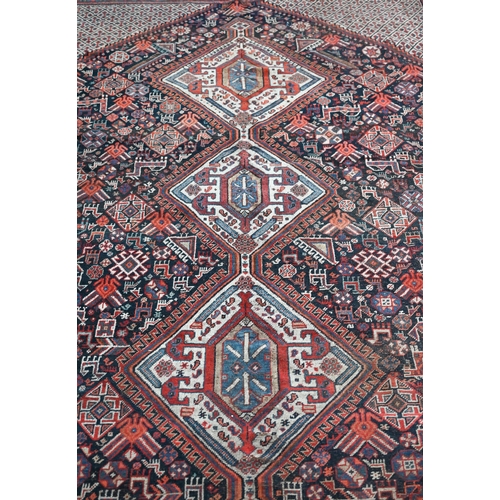 600 - An old Persian Shiraz, the triple medallion pole design on camel and blue ground, 280 cm x 202 cm