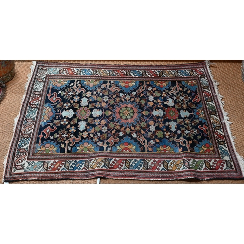 601 - An antique Caucasian blue ground rug, with geometric floral design, 144 cm x 115 cm