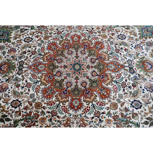 609 - An Indo-Persian Quom carpet, the camel ground centred by a floral medallion, the field woven with bi... 