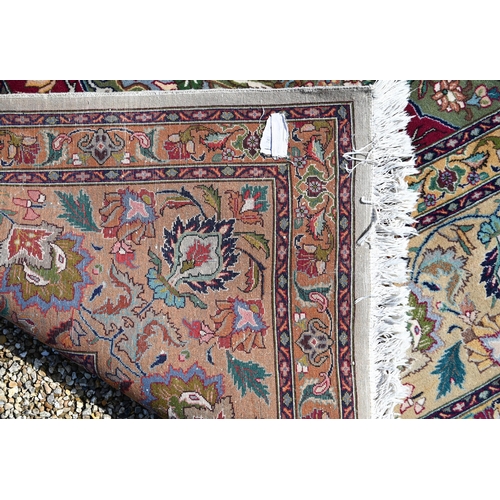 609 - An Indo-Persian Quom carpet, the camel ground centred by a floral medallion, the field woven with bi... 