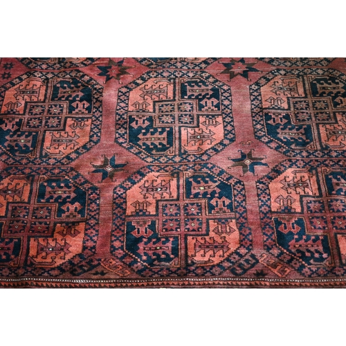 614 - An old Afghan red-brown ground carpet, the three rows of geometric guls, 322 cm x 237 cm, even wear,... 