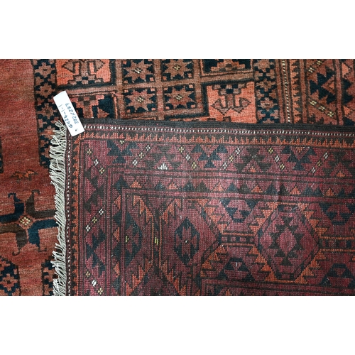 614 - An old Afghan red-brown ground carpet, the three rows of geometric guls, 322 cm x 237 cm, even wear,... 