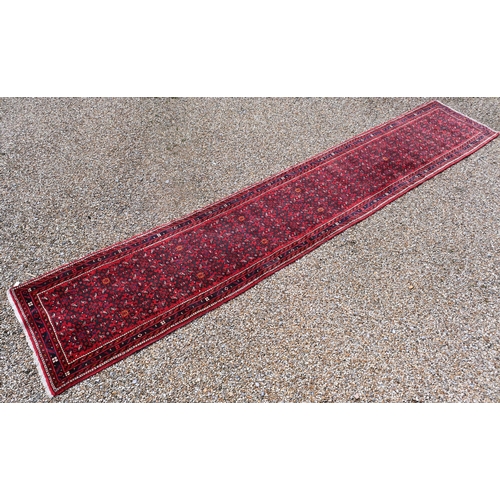 622 - A Persian Hamadan hall runner, the repeat design of stylised flowers on red ground, 515 cm x 85 cm