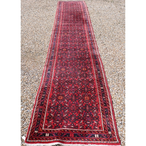 622 - A Persian Hamadan hall runner, the repeat design of stylised flowers on red ground, 515 cm x 85 cm