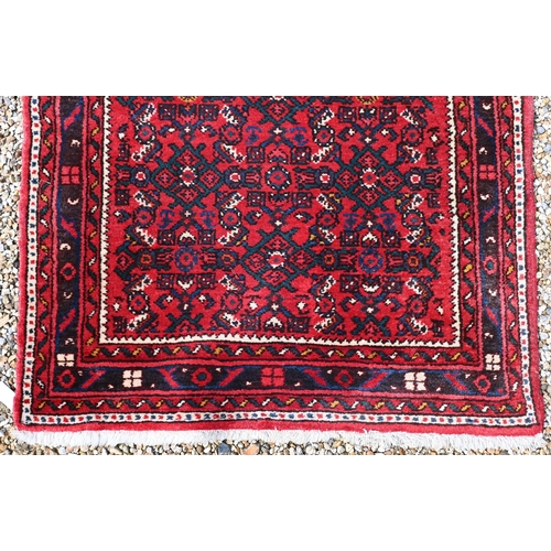 622 - A Persian Hamadan hall runner, the repeat design of stylised flowers on red ground, 515 cm x 85 cm