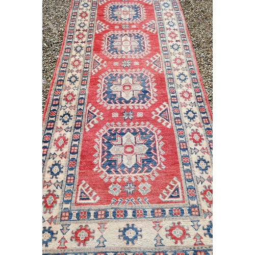 623 - A contemporary Agra runner, the pale coral ground with geometric floral design, 328 cm x 91 cm