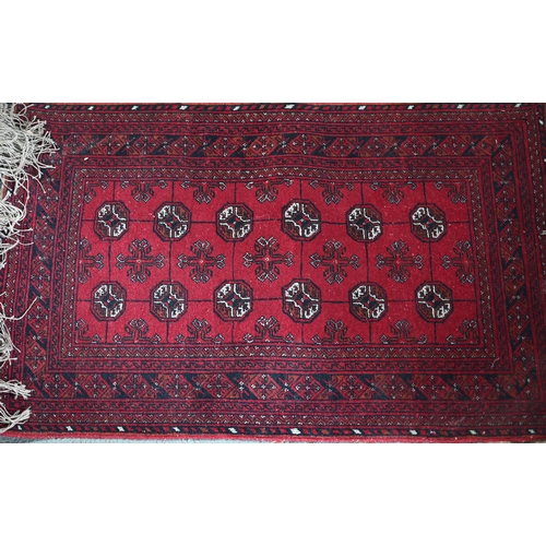 626 - An old Turkoman red ground rug, with three rows of geometric guls, 160 cm x 105 cm to/with a Pakista... 