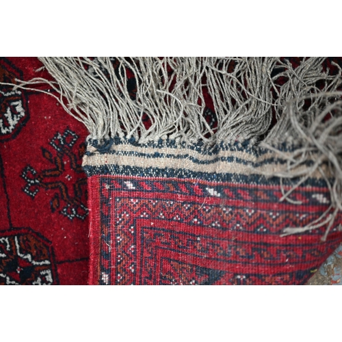 626 - An old Turkoman red ground rug, with three rows of geometric guls, 160 cm x 105 cm to/with a Pakista... 