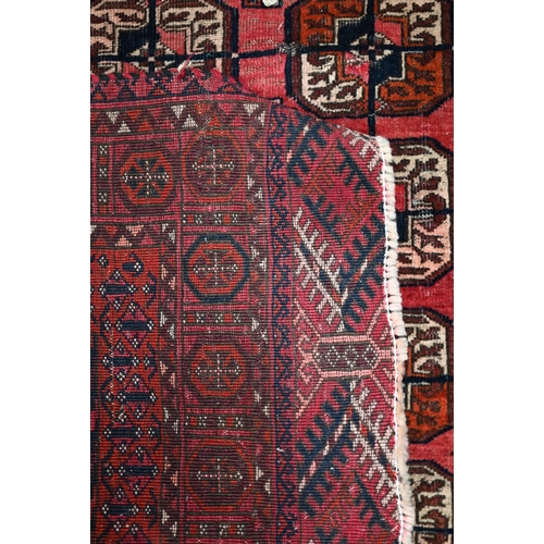 626 - An old Turkoman red ground rug, with three rows of geometric guls, 160 cm x 105 cm to/with a Pakista... 