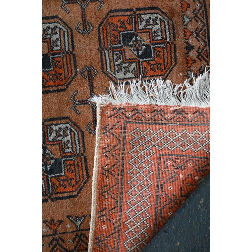 628 - An old golden ground washed Afghan rug, with three rows of stylised guls, 190 cm x 110 cm to/with an... 