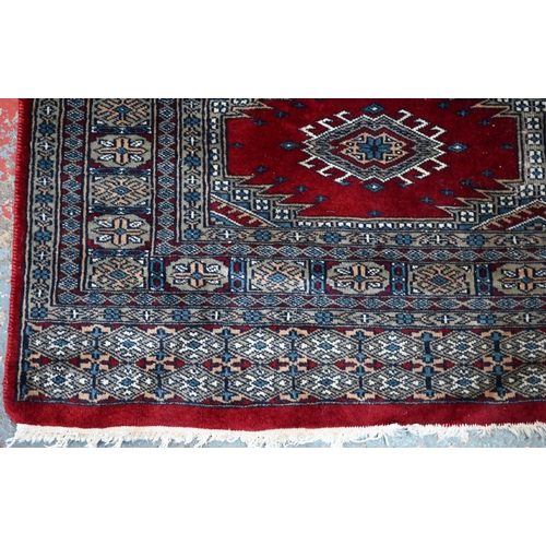 629 - A Persian Turkoman design red ground rug with geometric pole design, 200 cm x 120 cm