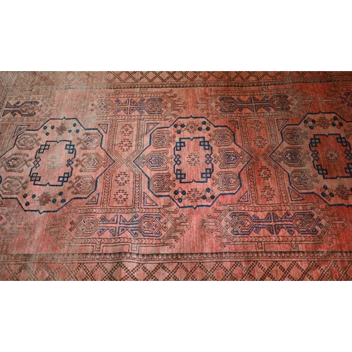 634 - An old Afghan pale red ground lozenge pole design rug, 220 cm x 133 cm, even wear, minor loss to end... 