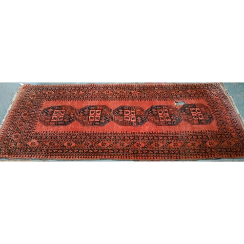 634 - An old Afghan pale red ground lozenge pole design rug, 220 cm x 133 cm, even wear, minor loss to end... 