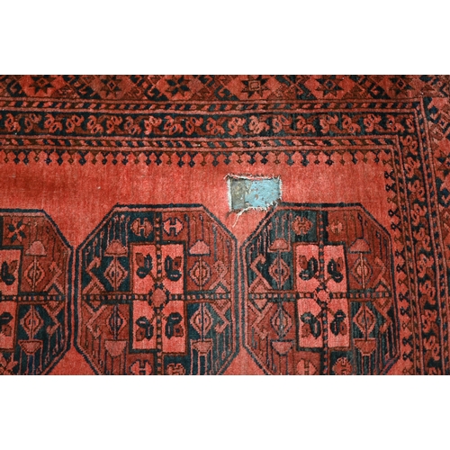 634 - An old Afghan pale red ground lozenge pole design rug, 220 cm x 133 cm, even wear, minor loss to end... 