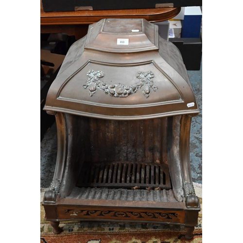 653 - An old cast iron and brass/copper mounted dog-grate, in the style of the Nautilus Stove Co., on rear... 