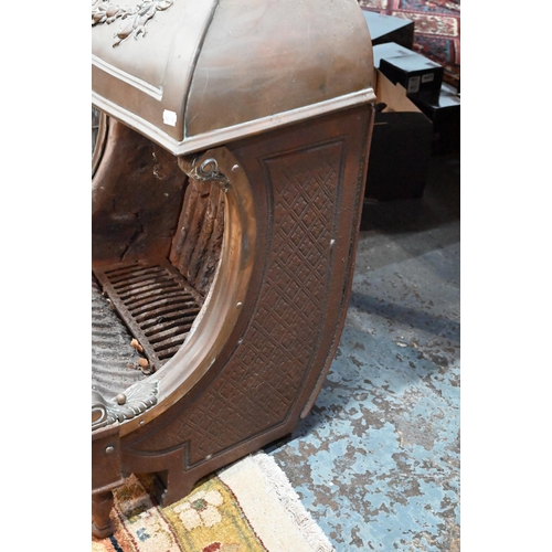 653 - An old cast iron and brass/copper mounted dog-grate, in the style of the Nautilus Stove Co., on rear... 