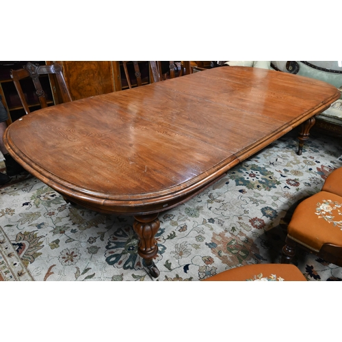 672 - A large Victorian oak extending dining table, the rounded ends united by two wide occasional leaves ... 