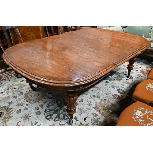 672 - A large Victorian oak extending dining table, the rounded ends united by two wide occasional leaves ... 