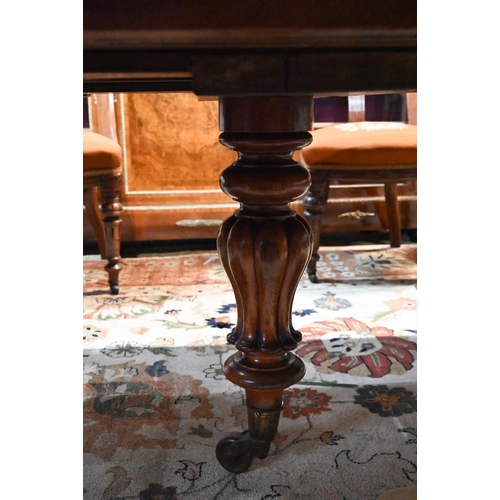 672 - A large Victorian oak extending dining table, the rounded ends united by two wide occasional leaves ... 