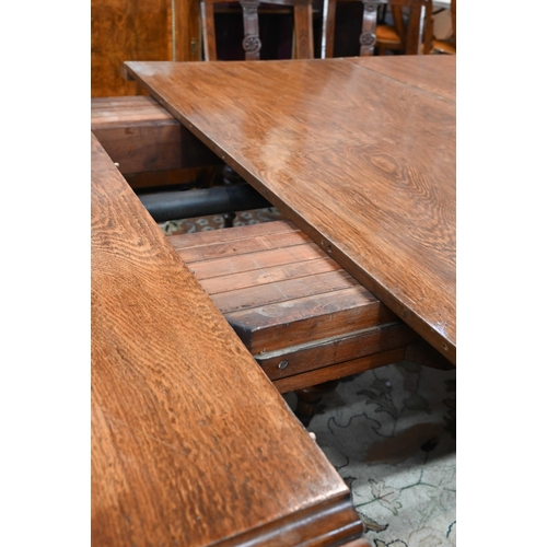 672 - A large Victorian oak extending dining table, the rounded ends united by two wide occasional leaves ... 