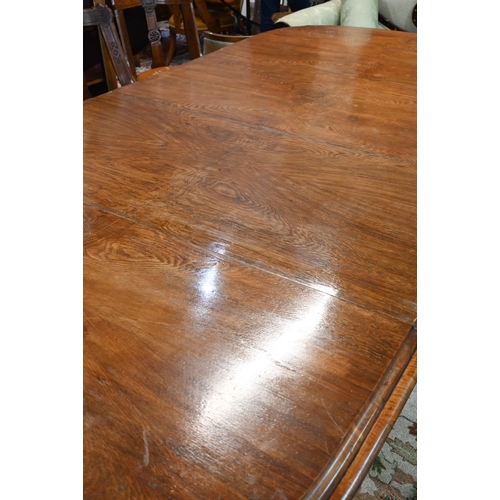 672 - A large Victorian oak extending dining table, the rounded ends united by two wide occasional leaves ... 