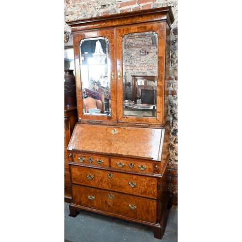 684 - An 18th century walnut bureau cabinet, the shaped cornice over two bevel edged mirror panelled doors... 