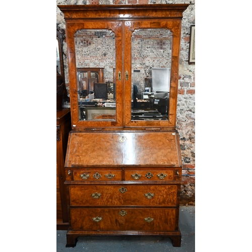 684 - An 18th century walnut bureau cabinet, the shaped cornice over two bevel edged mirror panelled doors... 