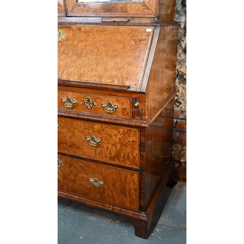 684 - An 18th century walnut bureau cabinet, the shaped cornice over two bevel edged mirror panelled doors... 