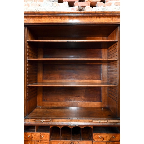 684 - An 18th century walnut bureau cabinet, the shaped cornice over two bevel edged mirror panelled doors... 