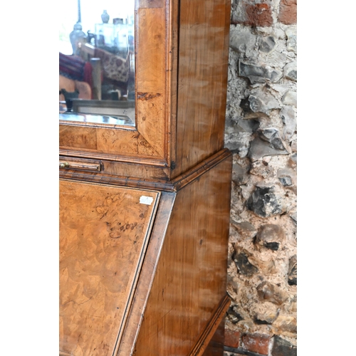 684 - An 18th century walnut bureau cabinet, the shaped cornice over two bevel edged mirror panelled doors... 