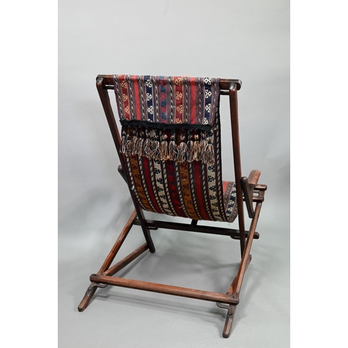 694 - An Afghan folding campaign chair, teak with steel mounts and a single spring action, fitted with a k... 