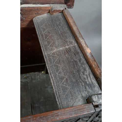 695 - A 17th century oak coffer, the wide two plank top over a lunette carved frieze and four diamond inci... 