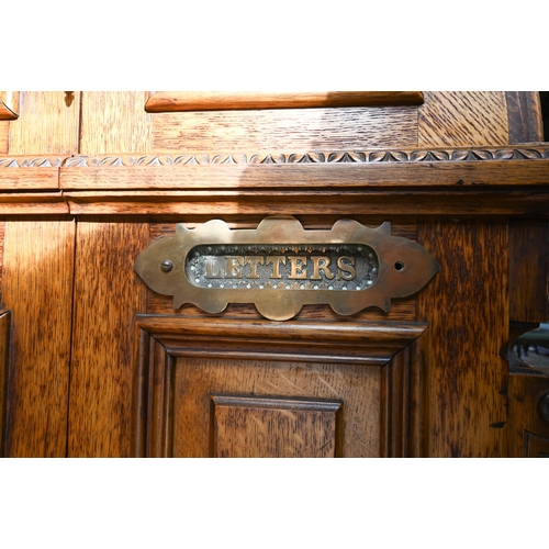 707 - An antique American Wells Fargo 'Wooton' style desk, golden oak, the hinged upper panel over a pair ... 