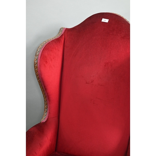 713 - A carved and moulded walnut framed burgundy plush upholstered armchair, with hump back over scroll a... 