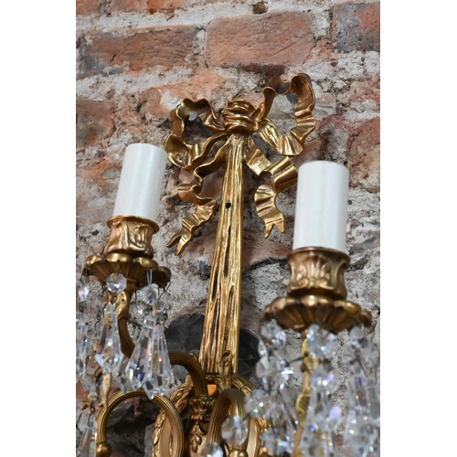 726 - A pair of Regency style ribbon and swag triple arm gilt metal wall sconces, crystal strung, 60 cm h ... 